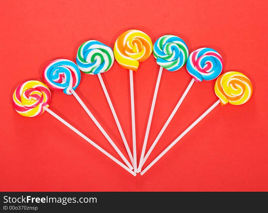 Twirl lollipop candies over a red background