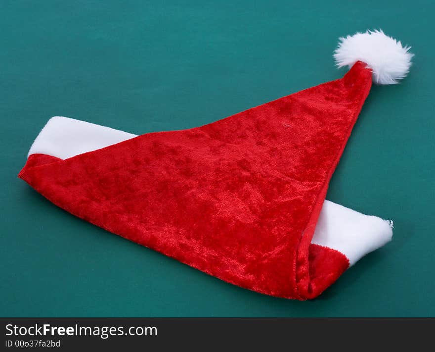 A red christmas hat over a green background