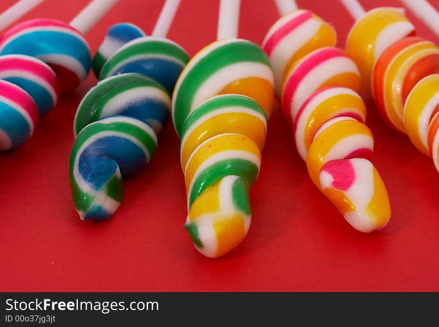 Twirl lollipop candies over a red background