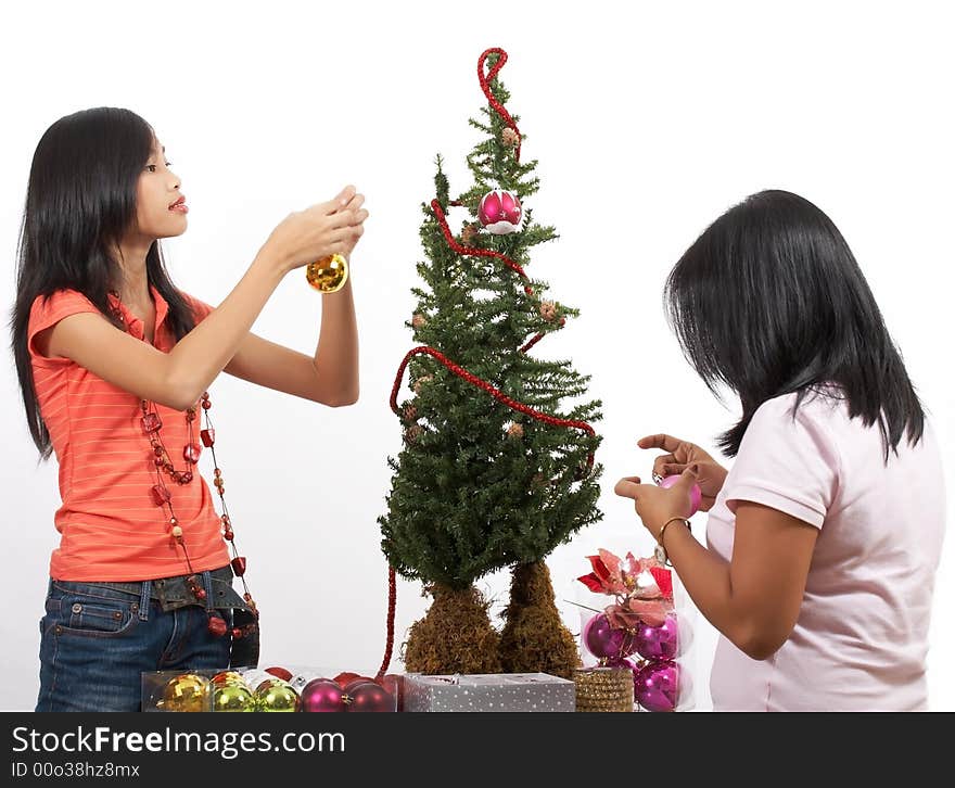 Two young girls decorating a christmas tree