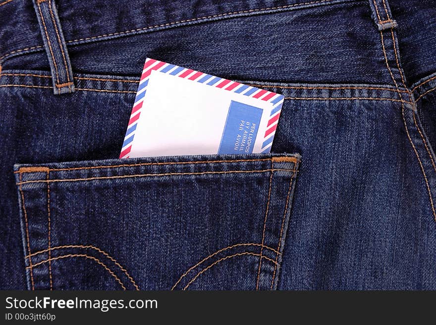 An air mail envelope in the back pocket of denim trousers.  Photographed in a studio. An air mail envelope in the back pocket of denim trousers.  Photographed in a studio.