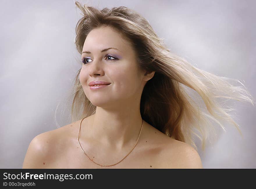 The beautiful young blonde on a grey background