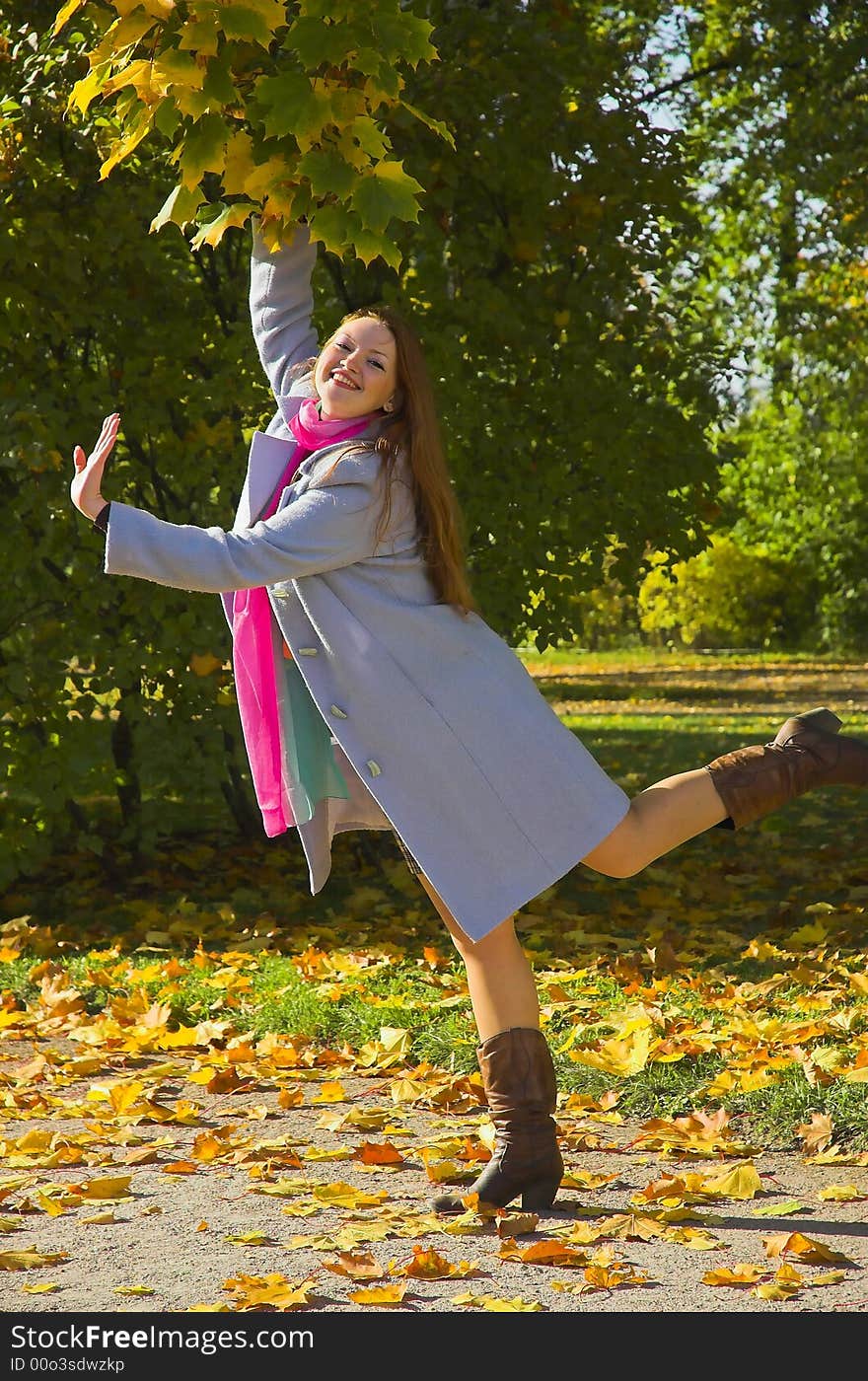 The cheerful beautiful girl in autumn park