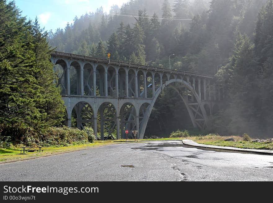 Old railroad bridge over modern paved road as the mist and fog burns off. Old railroad bridge over modern paved road as the mist and fog burns off