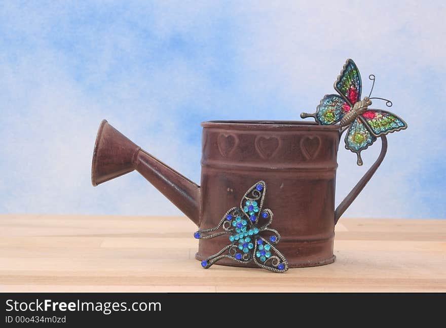 Metal Watering Can on Blue Sky Background With Betterflies. Metal Watering Can on Blue Sky Background With Betterflies