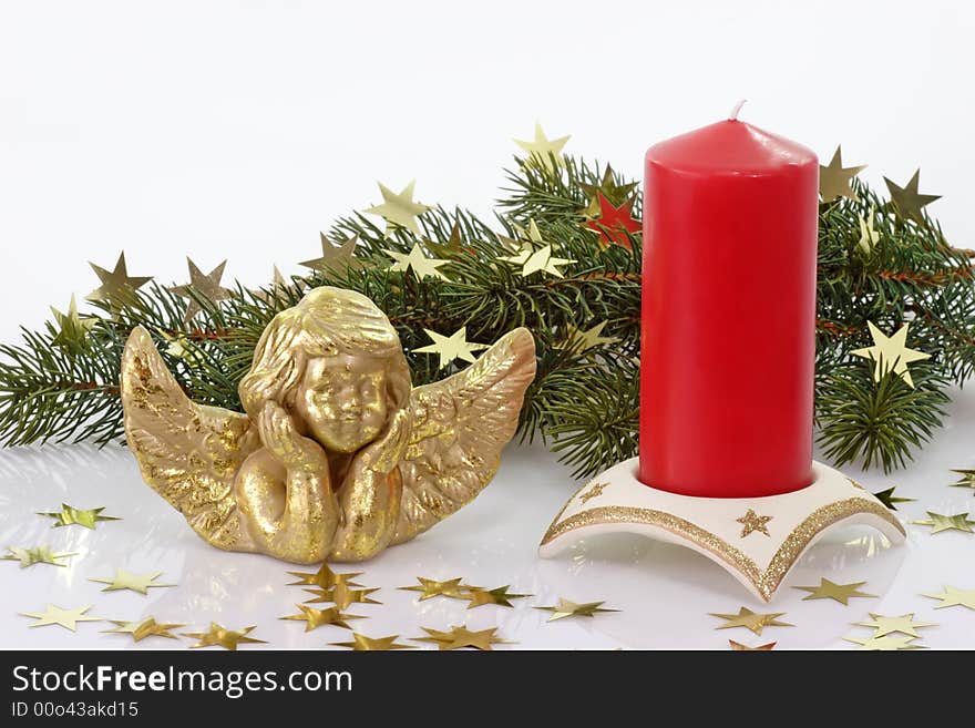 Golden angel figure with red candle and fir branch on light background