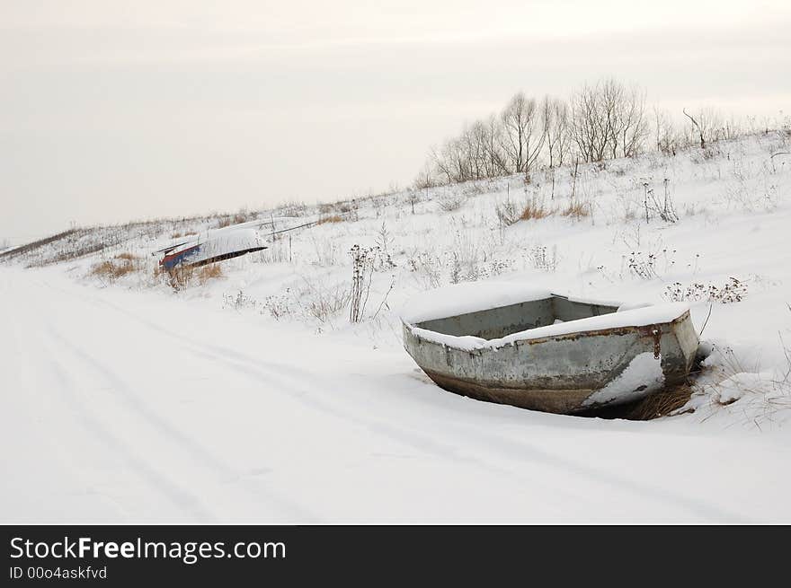 Boat on shore in snow, near road. Boat on shore in snow, near road