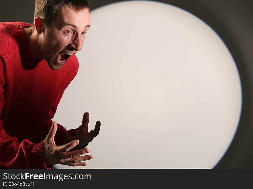 Young man in red pullover screaming and gesticulating - with a white circle in the background. Young man in red pullover screaming and gesticulating - with a white circle in the background.