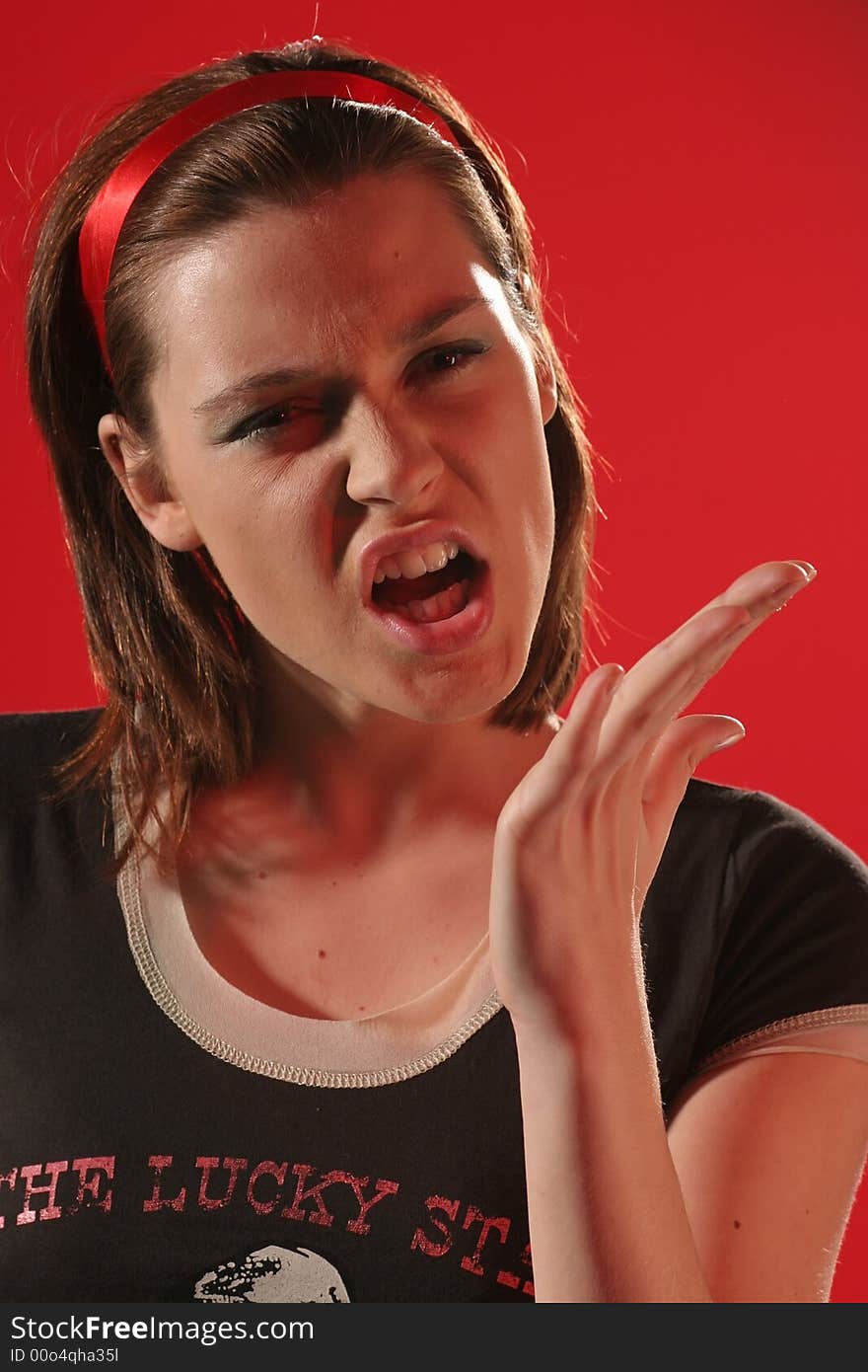 Young angry woman in a brown Tshirt on a red background making gesture. Young angry woman in a brown Tshirt on a red background making gesture.