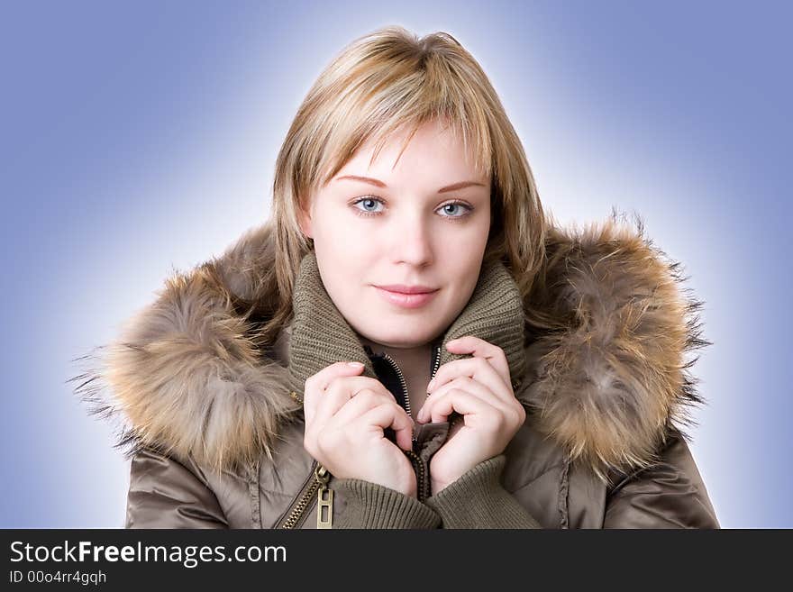 Young girl in a jacket with a fur collar on a light blue background