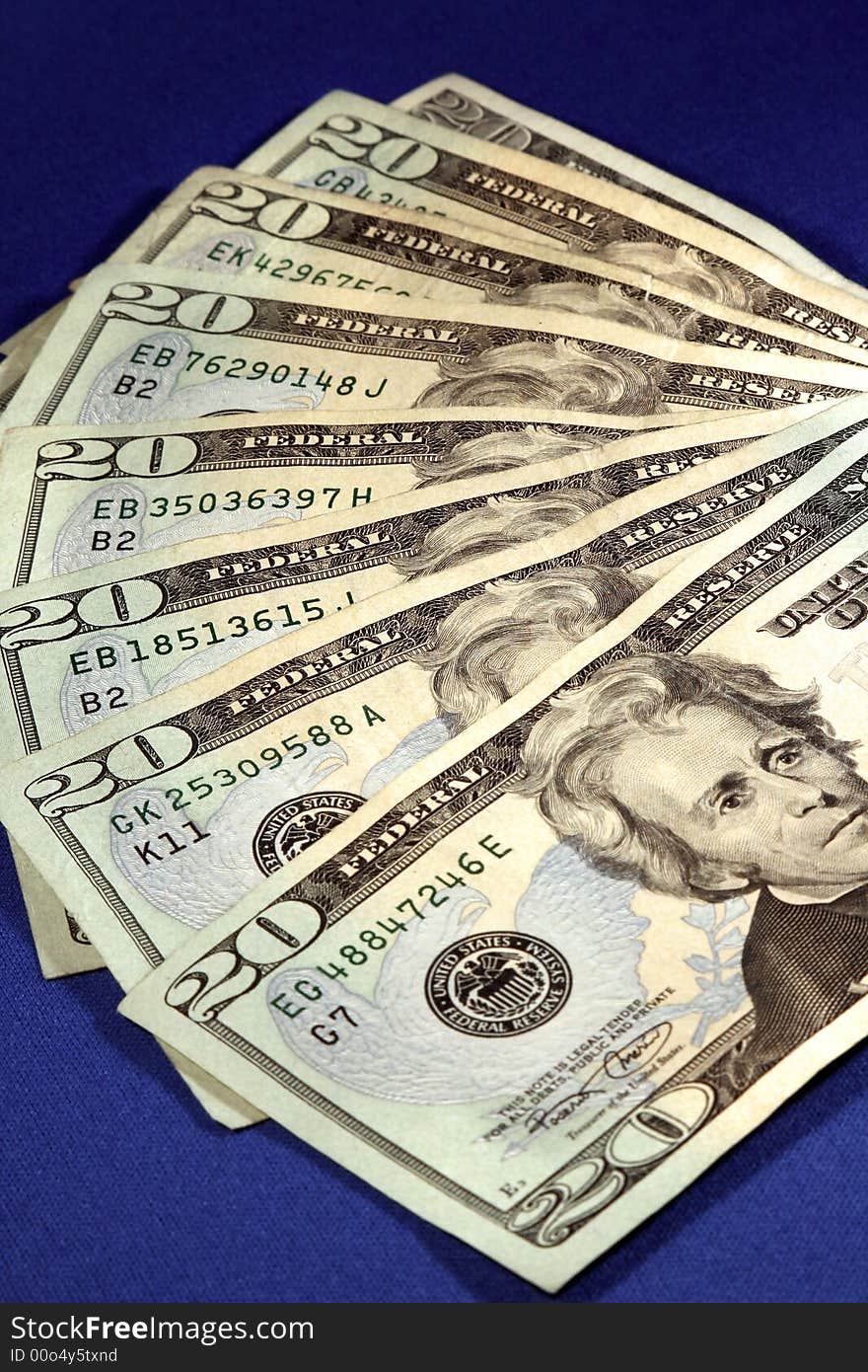 A closeup of twenty dollar bills shaped like a fan on a blue background. A closeup of twenty dollar bills shaped like a fan on a blue background