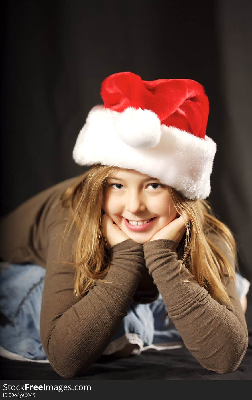 Cute young girl wearing a santa hat with a big smile on her face. Cute young girl wearing a santa hat with a big smile on her face