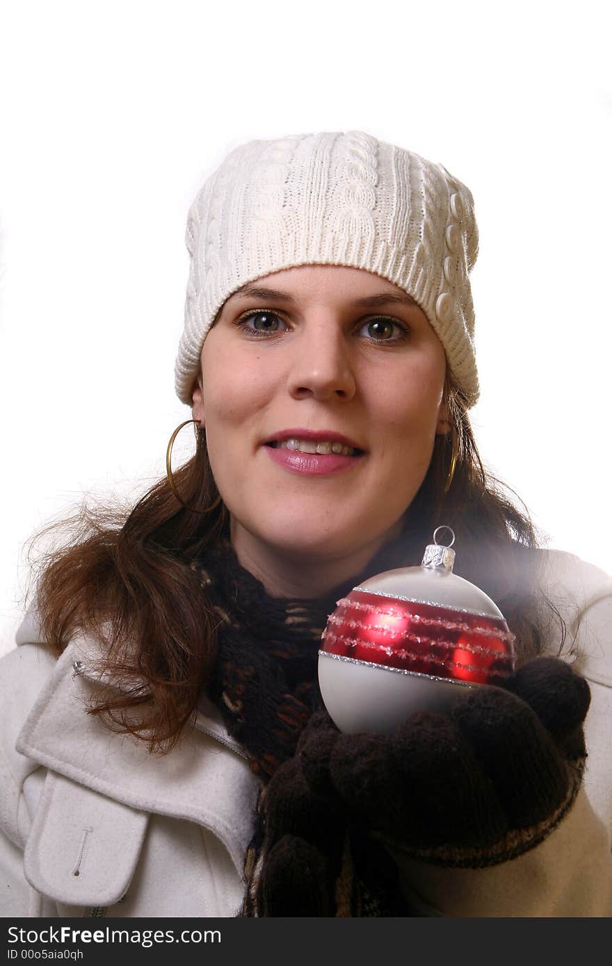 A young woman is holding christmas decoration. She is happy with winter gear on. Isolated over white with space for text. A young woman is holding christmas decoration. She is happy with winter gear on. Isolated over white with space for text.