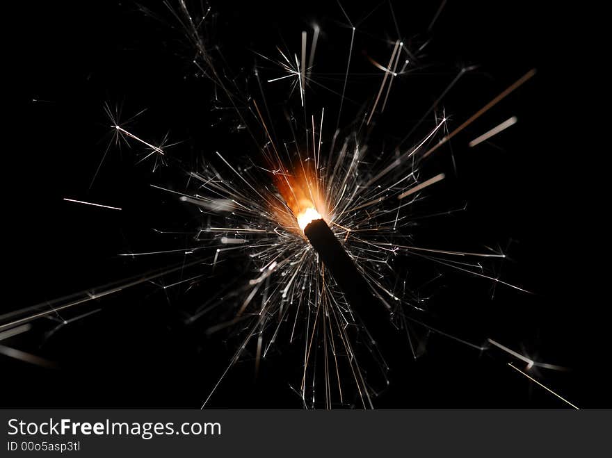 Burning sparkler against black background