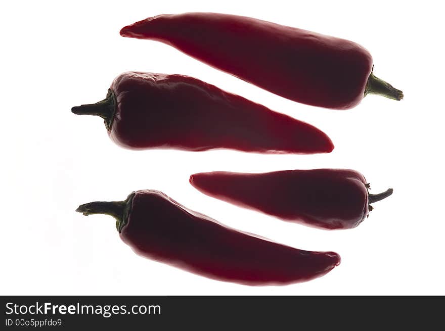 Backlit Red chilli peppers, isolated on a white background. Lit from underneath and shot overhead.