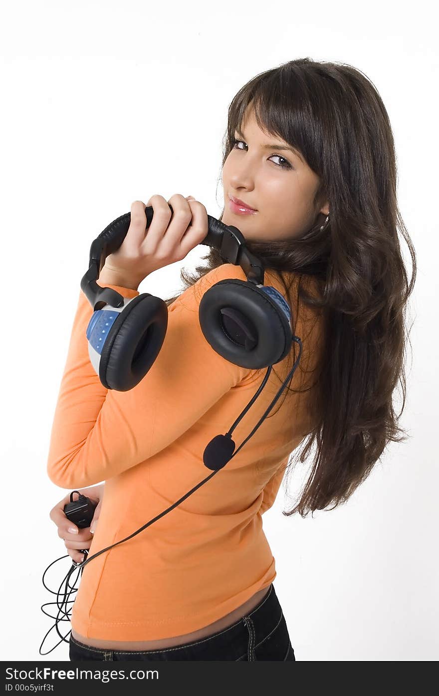 Beautiful brunette girl with headphones listening music and playing. Nice orange shirt.