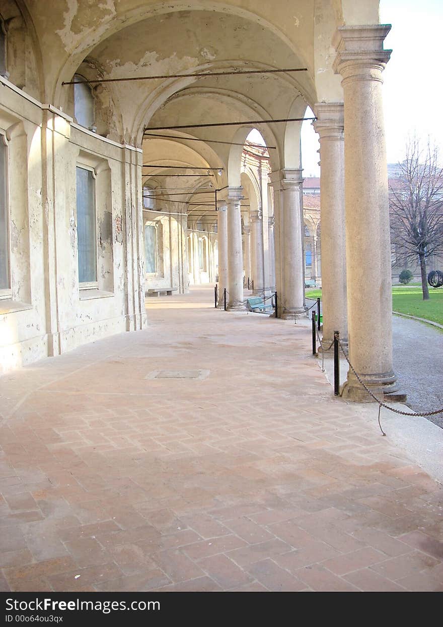 Some ancient colomns in a park around a historic building in Milan