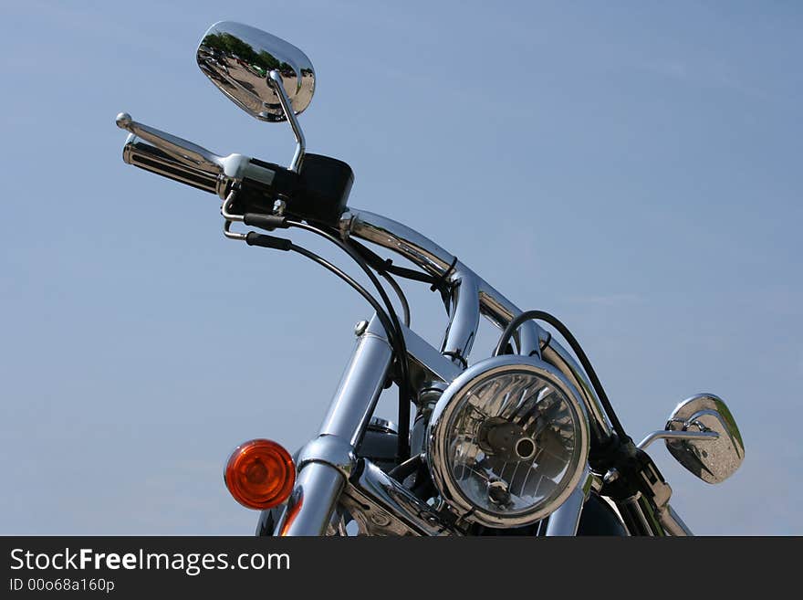 Handlebars and headlight on a chrome custom motorcycle. Handlebars and headlight on a chrome custom motorcycle