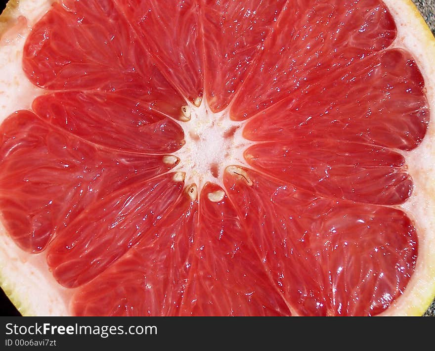 A cut red grapefruit open faced, view from above.