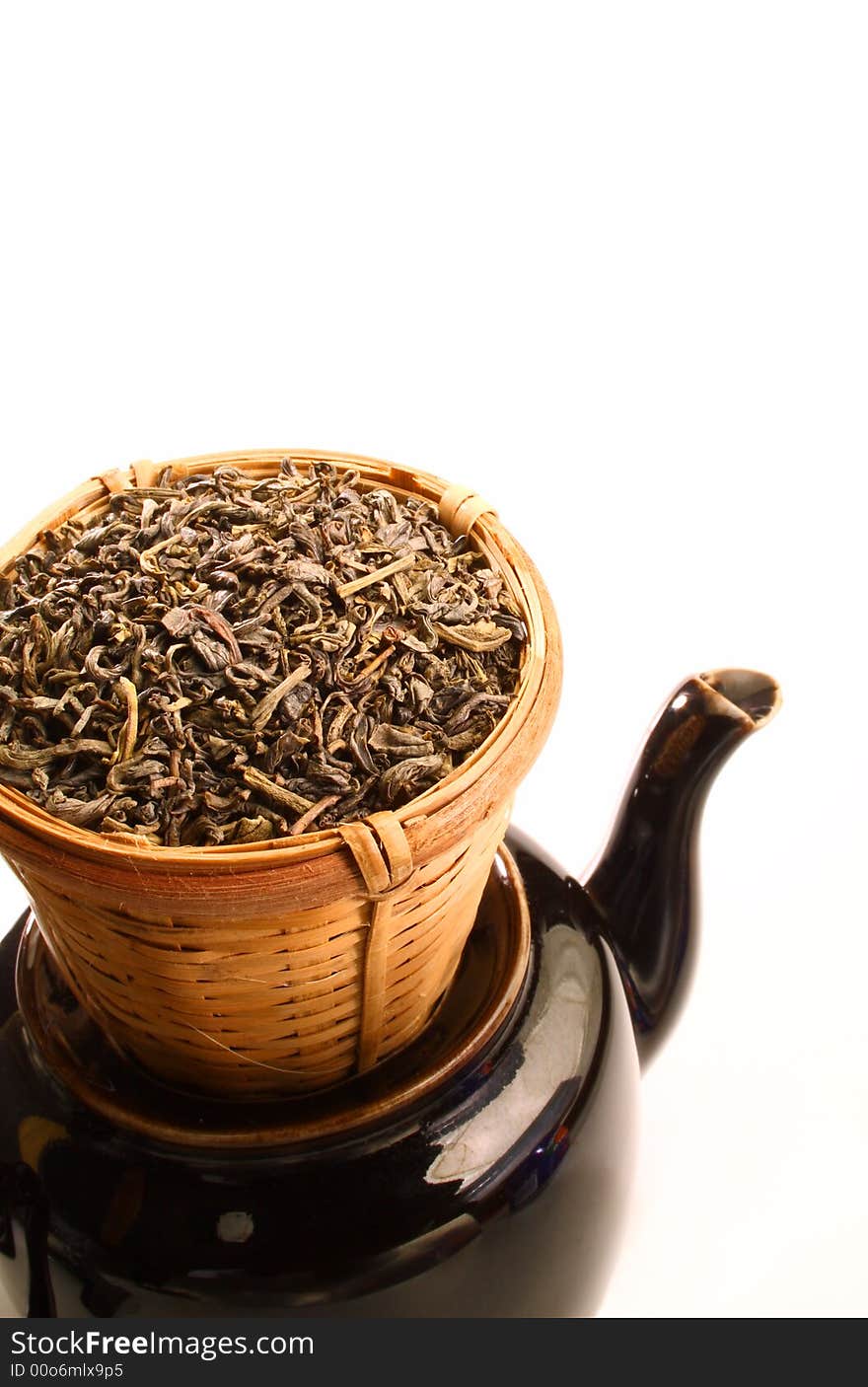 Green tea leaves in bamboo tea strainer on a tea pot. Green tea leaves in bamboo tea strainer on a tea pot.