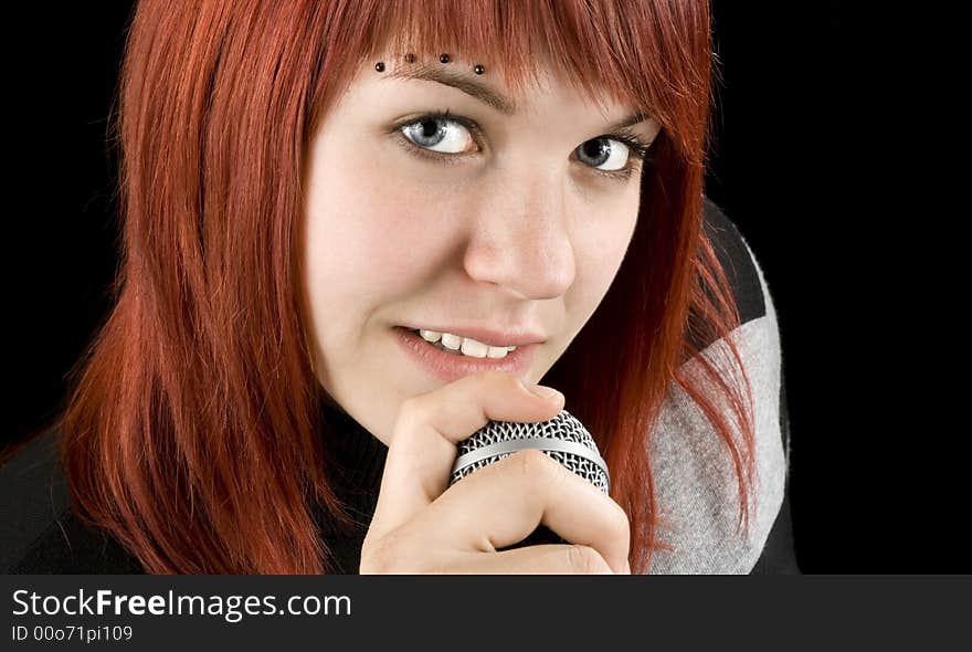 Cute smiling redhead girl singing on microphone.

Studio shot.