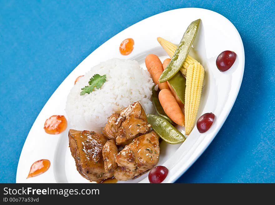 Colorful Tai sticky chicken dish taken over a blue background.