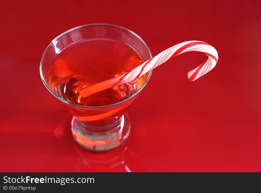 A christmas martini with a candy cane on a red background. A christmas martini with a candy cane on a red background