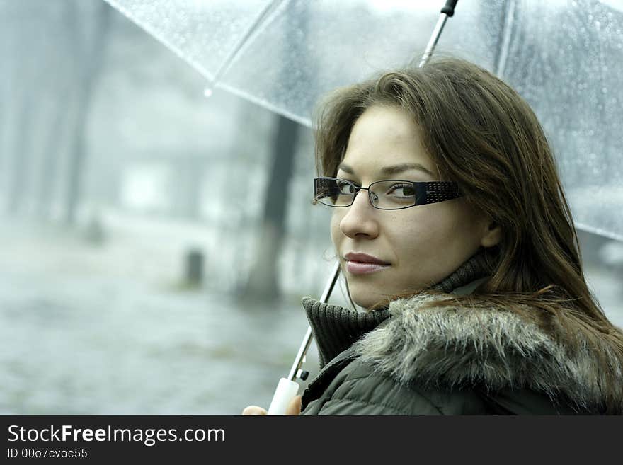 The girl with an umbrella stands under rain. The girl with an umbrella stands under rain