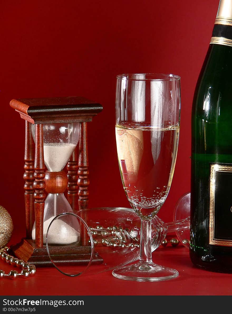 New year‘s still life with sandglass and champagne on the red. New year‘s still life with sandglass and champagne on the red