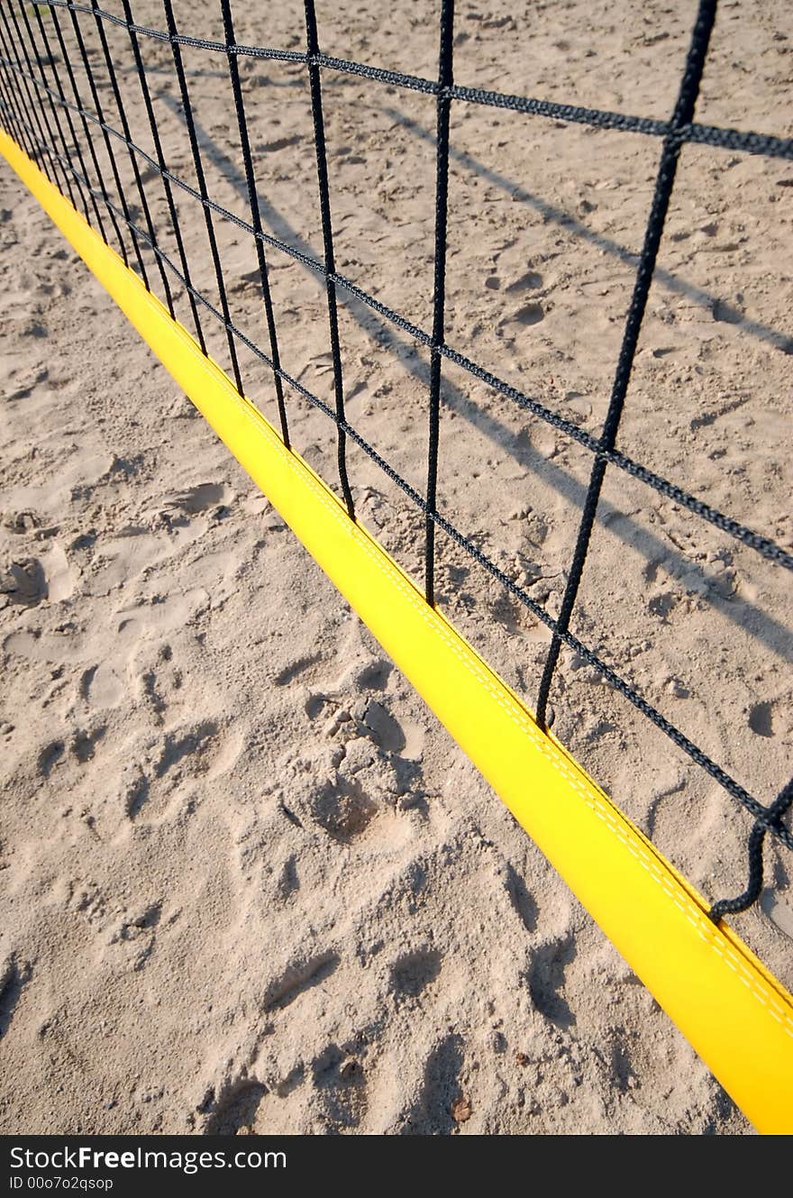 Yellow volleyball net shot from above, visible sand