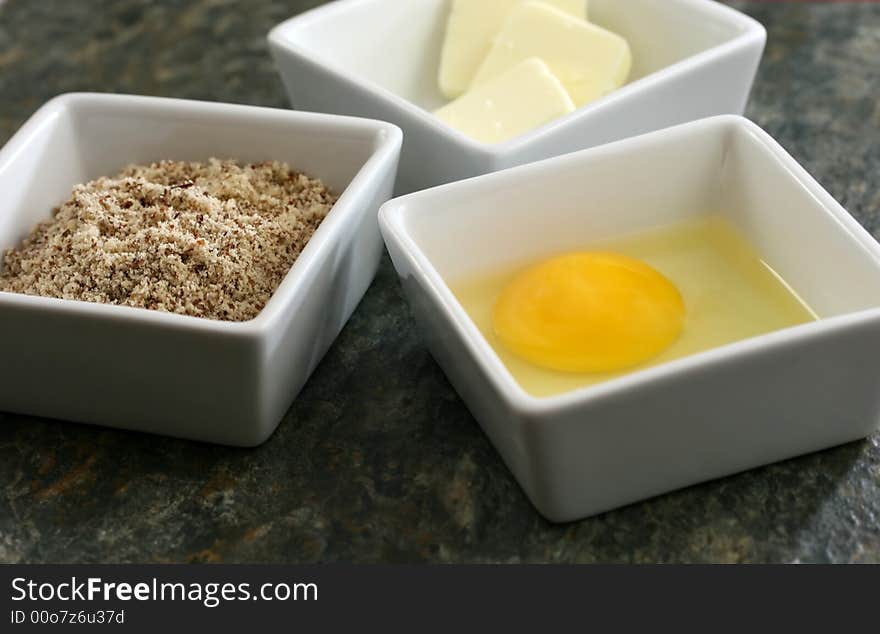 Raw eggs, butter and flour on a granite countertop. Raw eggs, butter and flour on a granite countertop