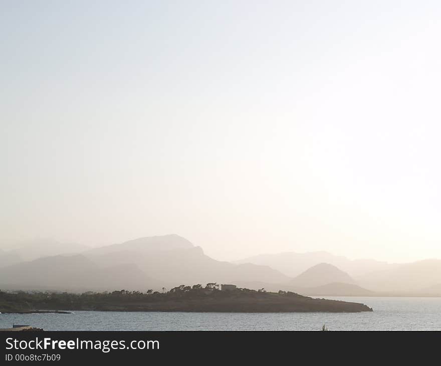 A sea side resort landscape when the sun goes down with mountains at the back