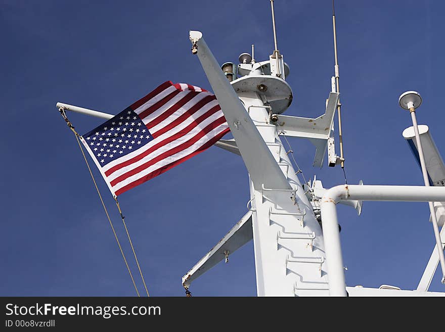 Us Flag on top of a ferry boat flying against the blue sky with a hint of clouds. Us Flag on top of a ferry boat flying against the blue sky with a hint of clouds.