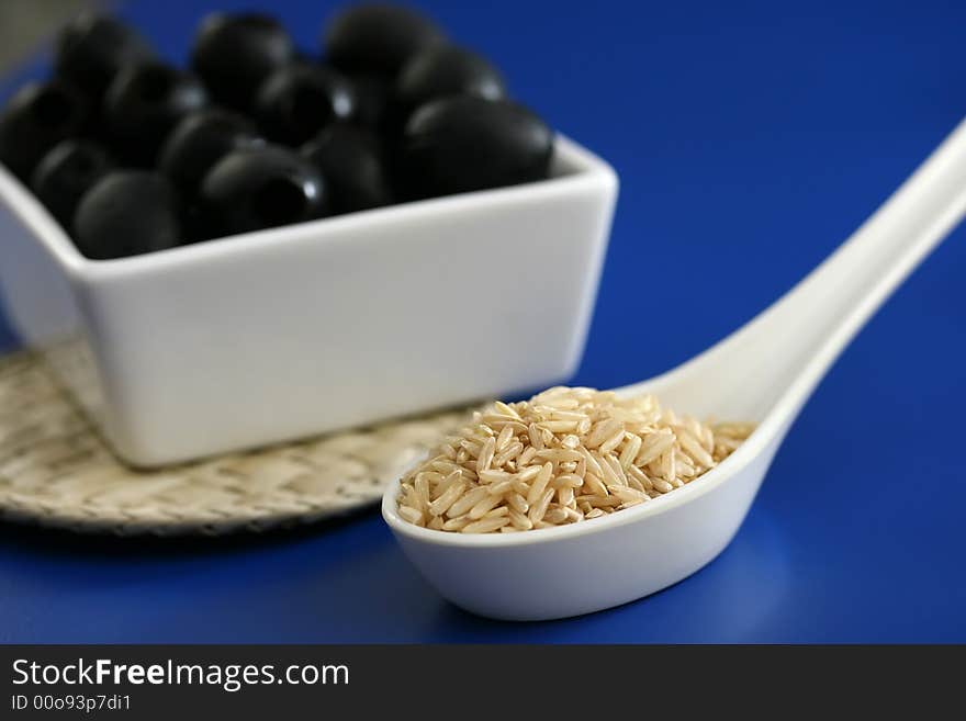 Black olives, brown rice, Ingredients for cooking on a blue tabletop. Black olives, brown rice, Ingredients for cooking on a blue tabletop