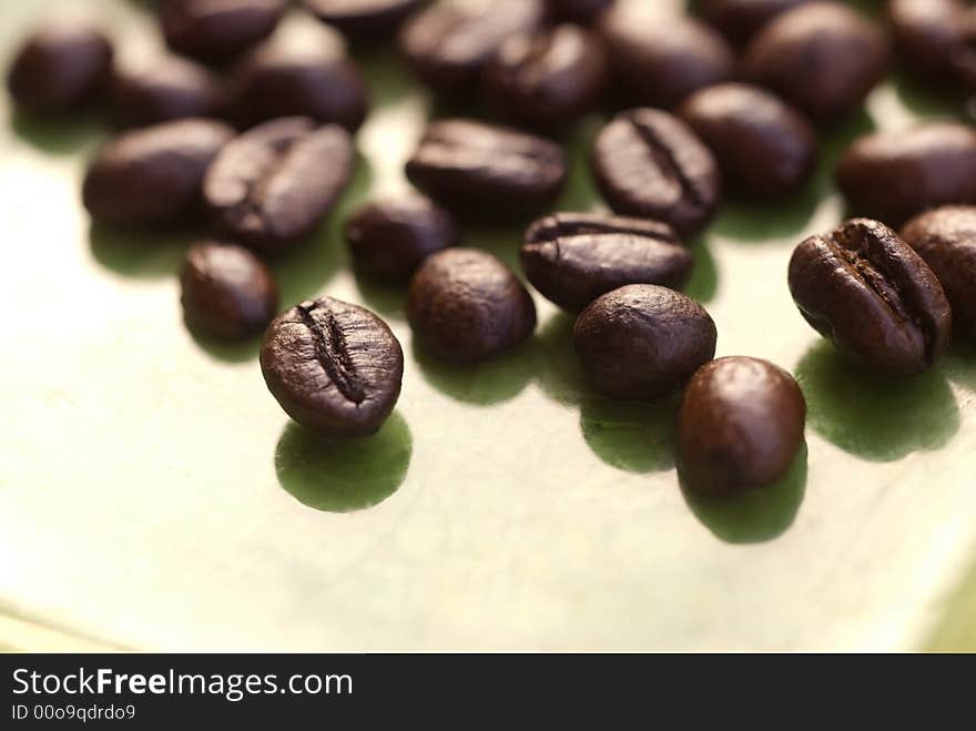 A close up image of coffee beans on agreen background. A close up image of coffee beans on agreen background