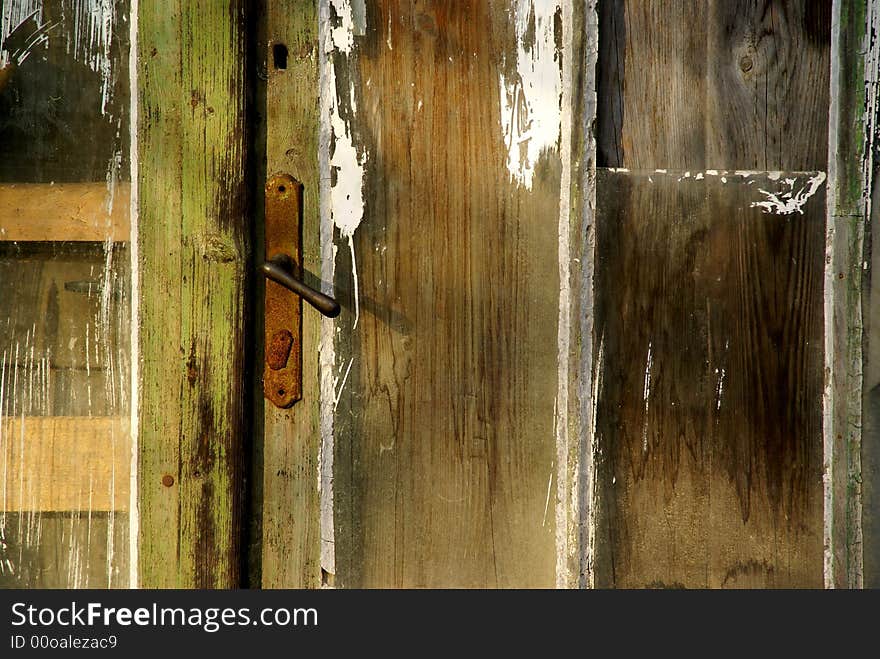 Old wooden door with rusted handle and interesting texture.