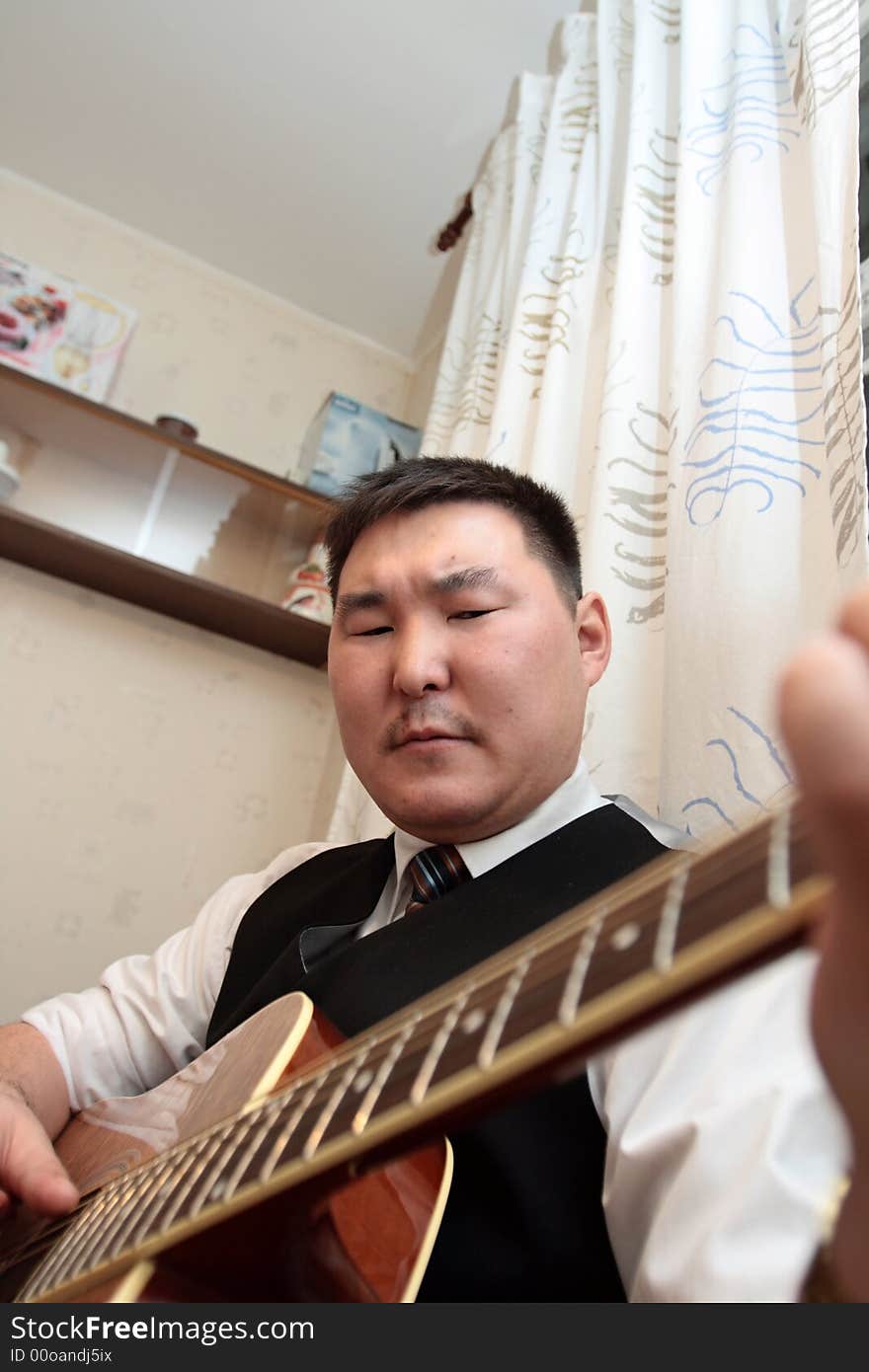 The man playing the guitar at home. The man playing the guitar at home