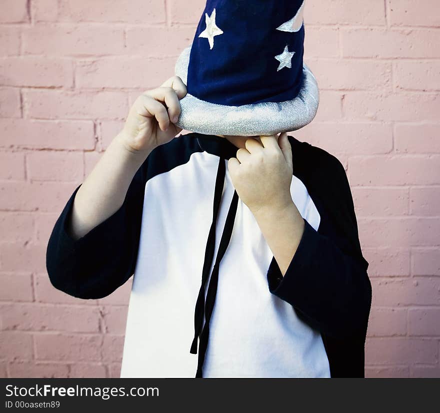 Little boy in a sorcerer hat picks his nose