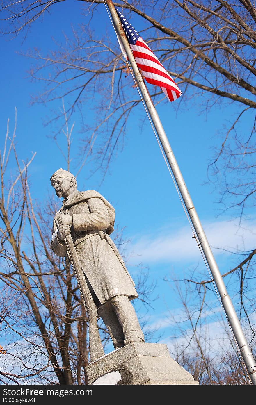 A civil war soldier statue with the American flag. A civil war soldier statue with the American flag