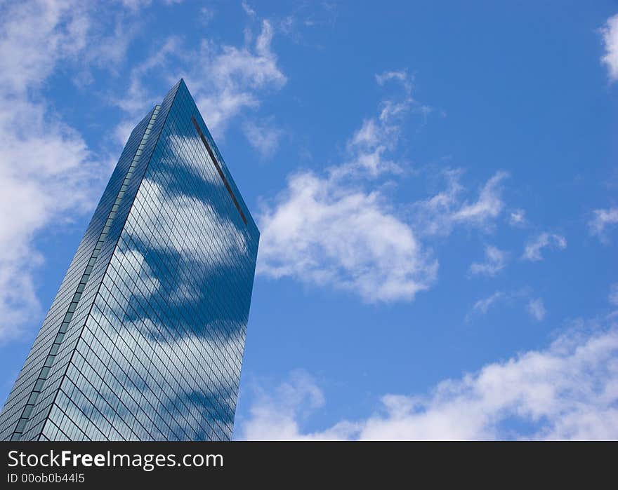 The John Hancock tower in Boston reflecting clouds on a sunny day.