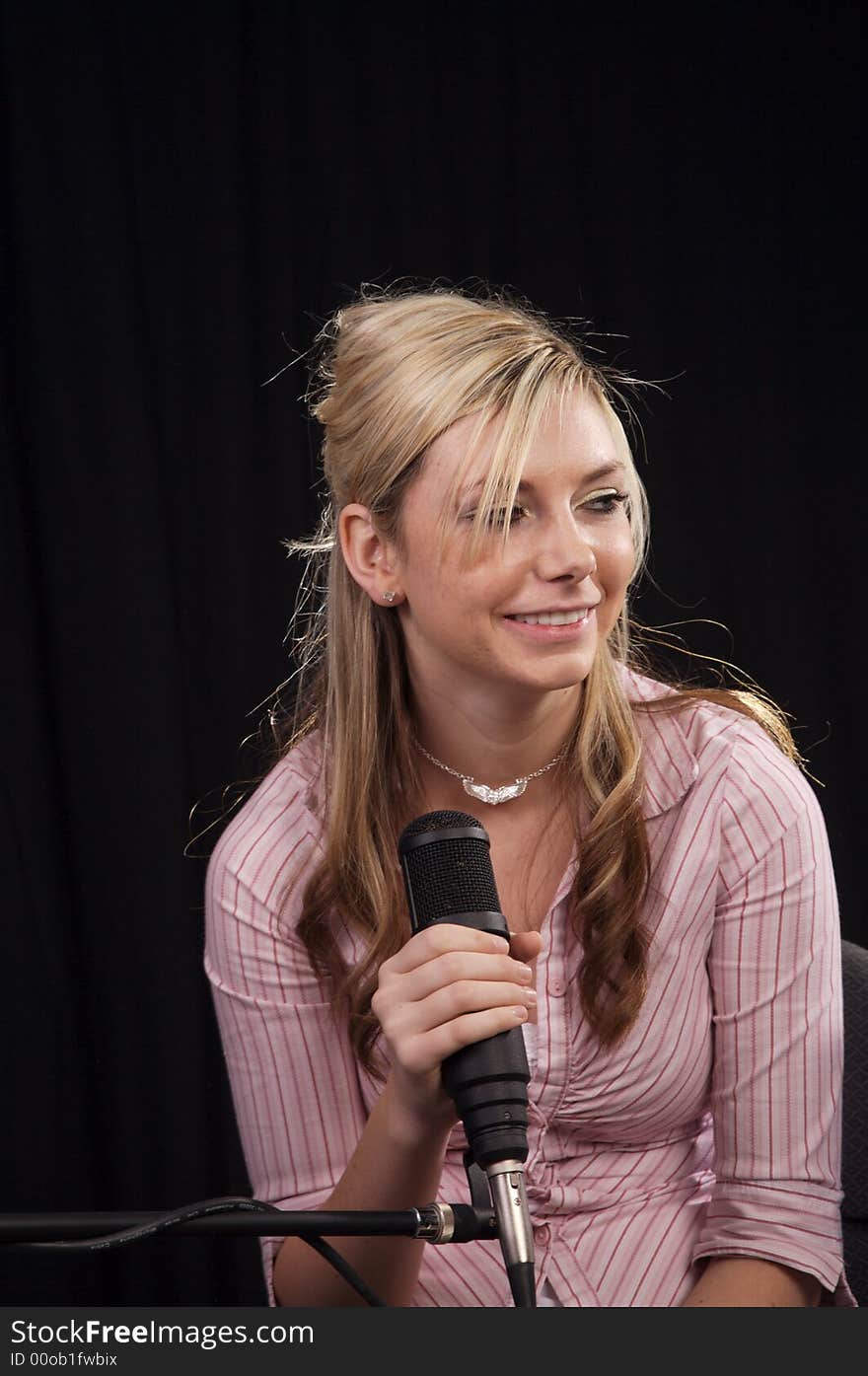 Beautiful young woman singing into a microphone. Beautiful young woman singing into a microphone