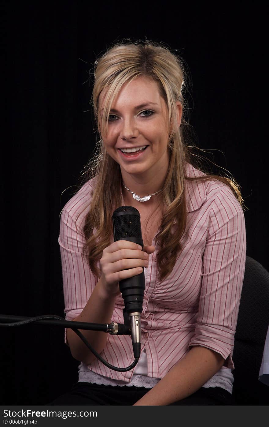 Beautiful young woman singing into a microphone. Beautiful young woman singing into a microphone