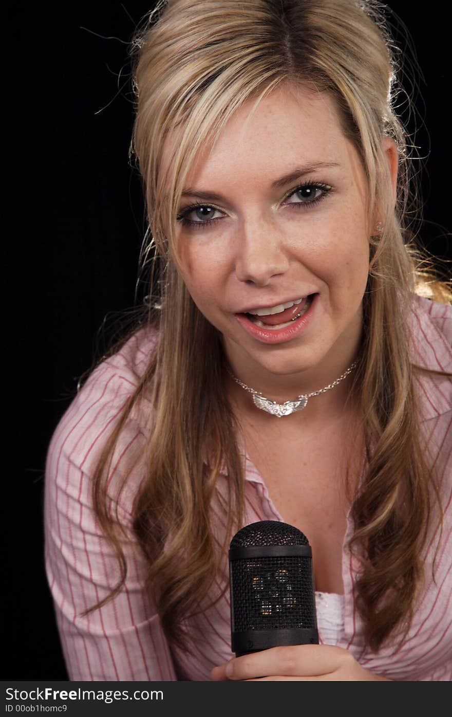 Beautiful young woman singing into a microphone. Beautiful young woman singing into a microphone