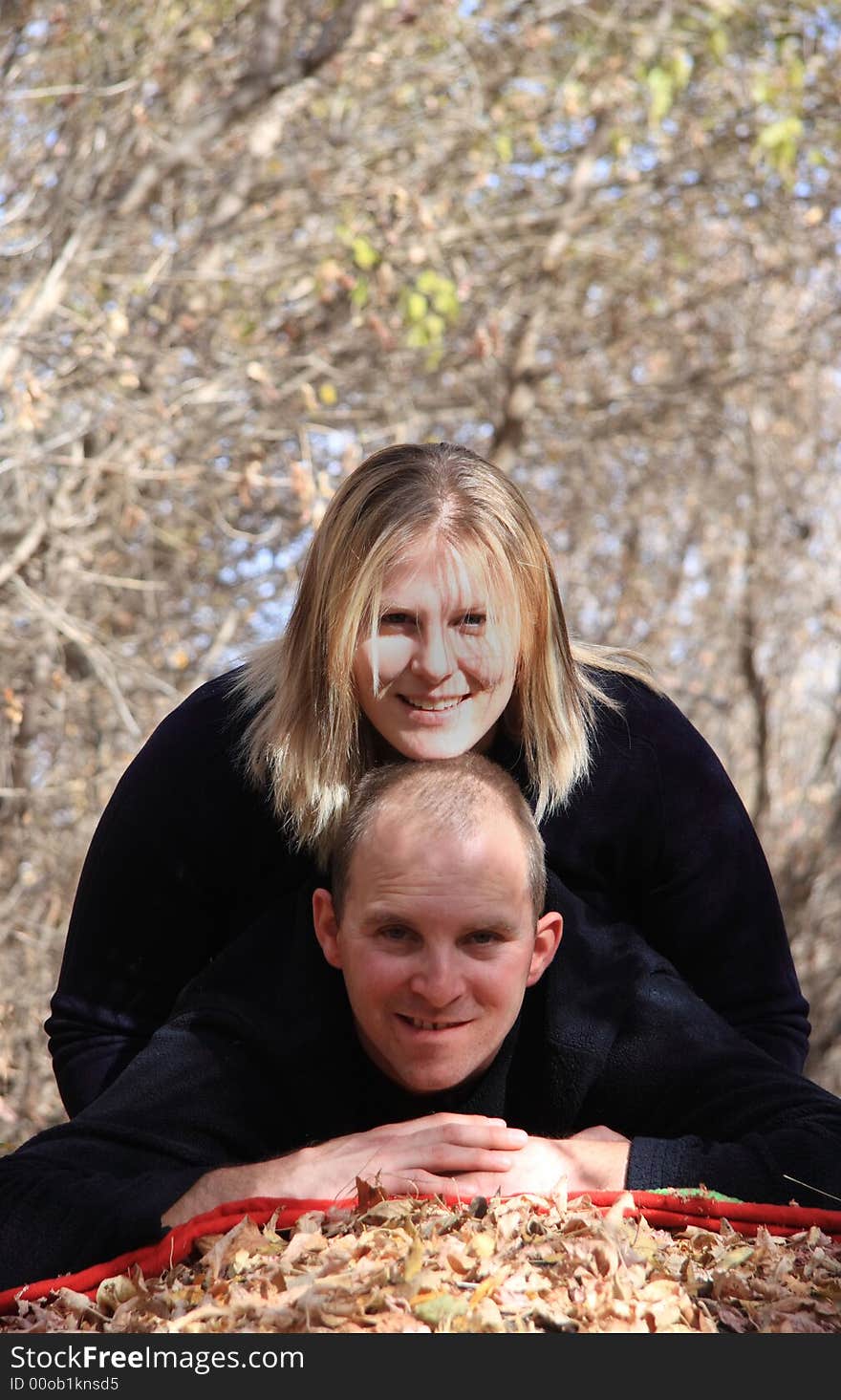 A happy young couple enjoying and playing around in an Autumn forest. A happy young couple enjoying and playing around in an Autumn forest.