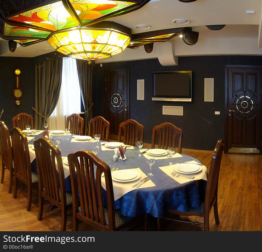 Lunch room with a large chandeliers. Chandeliers made of colored glass. Hall without bright. Cozy. In dark tones.