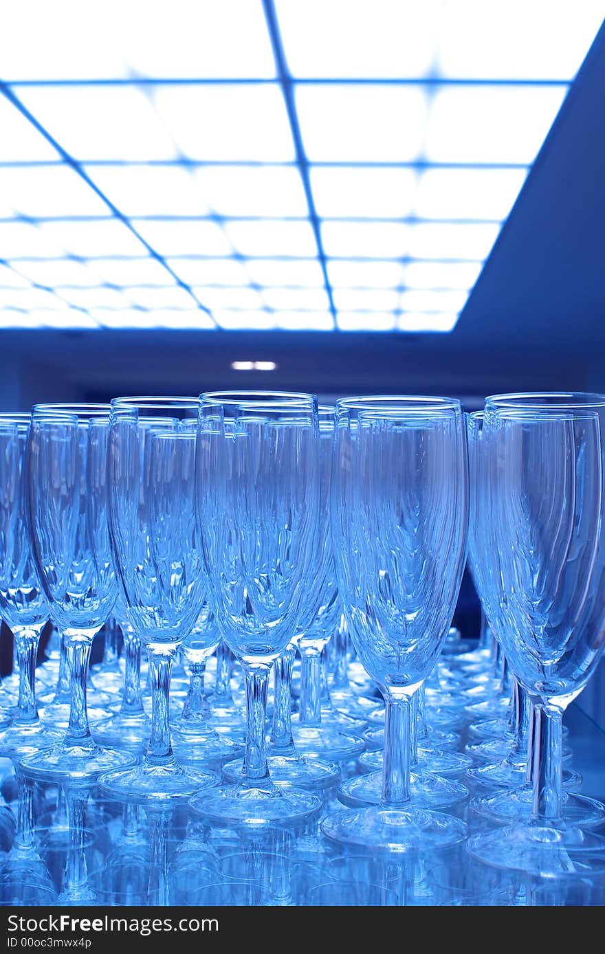 Bunch of empty champagne glasses at party, blue tones.