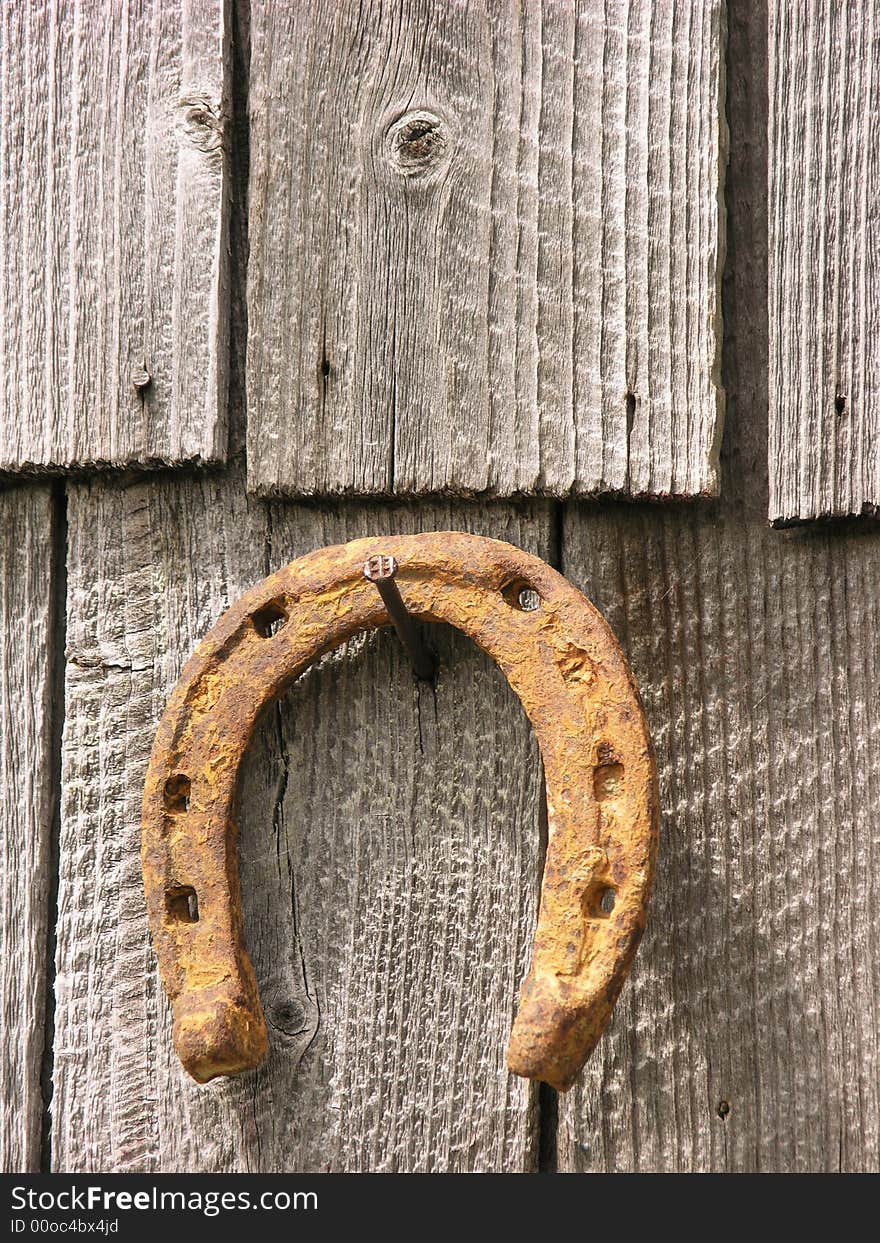 Rusty dry horseshoe pin on a nail at old wood tiles background. Rusty dry horseshoe pin on a nail at old wood tiles background