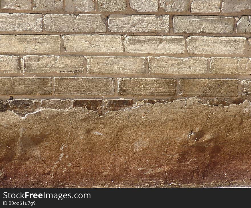 Exposed brick wall behind an eroded cement overlay