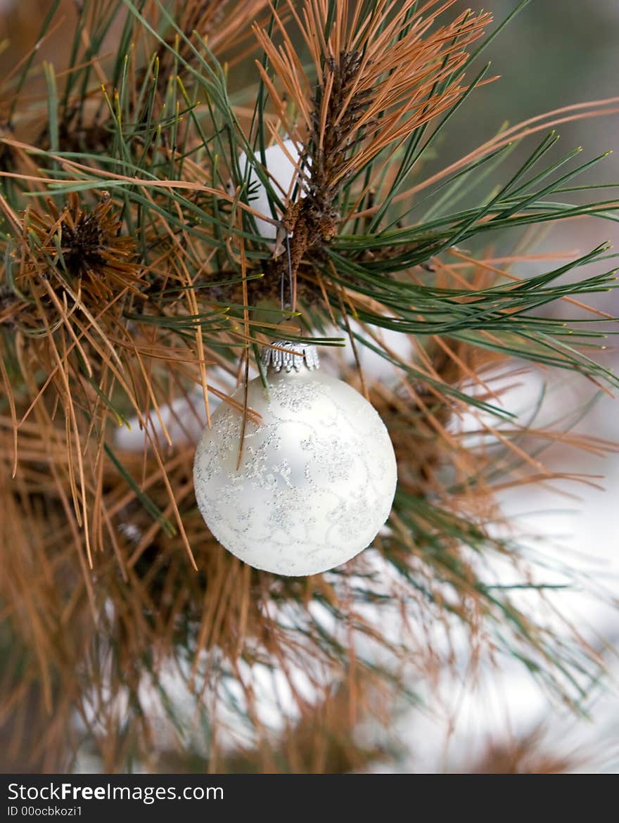 White and Silver Christmas Ornament in a snowy pine tree