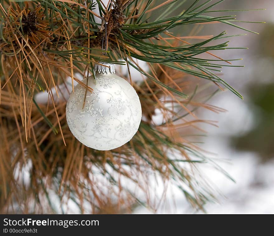 White and Silver Christmas Ornament in a snowy pine tree